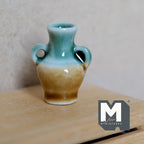 1:12 scale miniature ceramic amphora vase with 2 handles, glossy turquoise and amber glaze, shown on a wood dresser