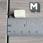 1:12 scale miniature soap pump dispenser in beige with a bronze pump, square bottle shown lying beside a ruler