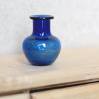 1:12 scale miniature blue glass vase, round with short neck, deep cobalt color, shown on a wood dresser