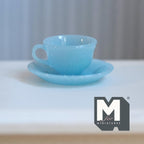 1:6 scale miniature teacup and saucer with fluted floral pattern in translucent light blue, on a white table