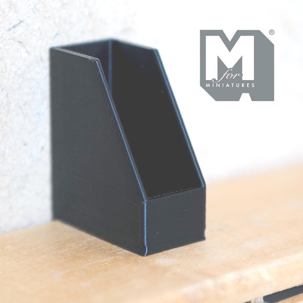 1:12 scale miniature magazine file holder for office desk in black with slanted sides, shown on a wood shelf