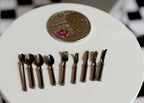 1:12 scale miniature metal flatware set in bronze, 9 pieces, spoons, forks and knives shown beside a coin for scale