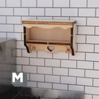 1:12 scale miniature wood heart cutout wall shelf kit with 2 coat pegs, shown assembled on a white tile wall
