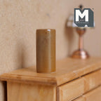 1:12 scale miniature ceramic cylinder vase in glossy brown, shown on a wood dresser beside a lamp