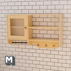 1:12 scale miniature wall cabinet in cream with a fluted door, open shelves and pegs, shown on a white tile wall