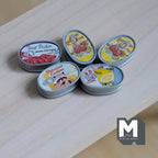 1:12 scale miniature oval food cans in resin, set of 5, assorted colorful labels, shown on a light wood surface