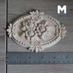 1:12 scale miniature oval multi layer leaf ceiling rose in bare wood with carved flowers, shown with a ruler