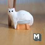 1:12 scale miniature white cat sitting on a stool in resin, fluffy white cat on a small orange stool, on a wood floor