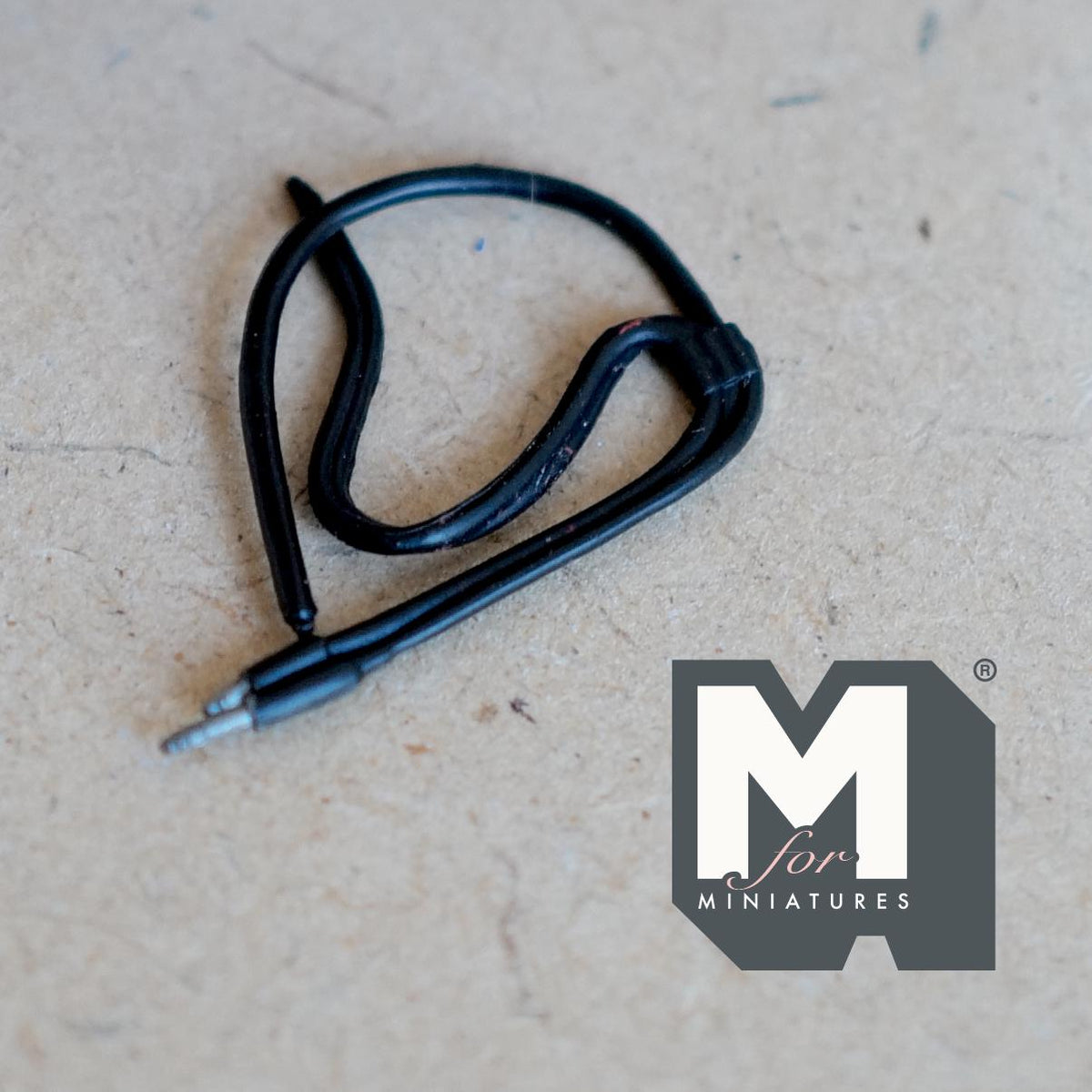 1:12 scale miniature non working headphone cable with jack plug in black, coiled, shown on a tabletop