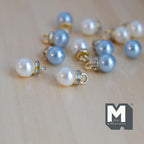 1:12 scale miniature pearlescent Christmas baubles in blue and white with gold caps, set of 12, on a wood floor