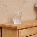 1:12 scale miniature ribbed glass flower pot in clear with a tapered shape, shown on a wood dresser