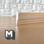 1:12 scale miniature grooved wood baseboard molding in white, close view of the profile end on a wood surface