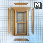 1:12 scale miniature double hung window with dentil pediment in bare wood, back trim pieces laid out on a grid mat