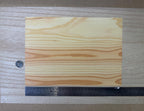 1:12 scale miniature cedar peel and stick wood veneer sheet in natural tone with bold grain, shown with a ruler and coin