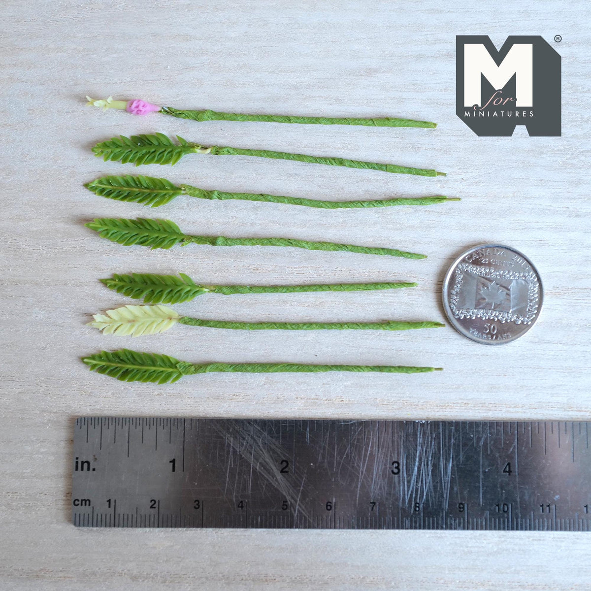 1:12 scale miniature green feathery fern frond stems with one pale cream green frond and a pink bud, on green wrapped stems