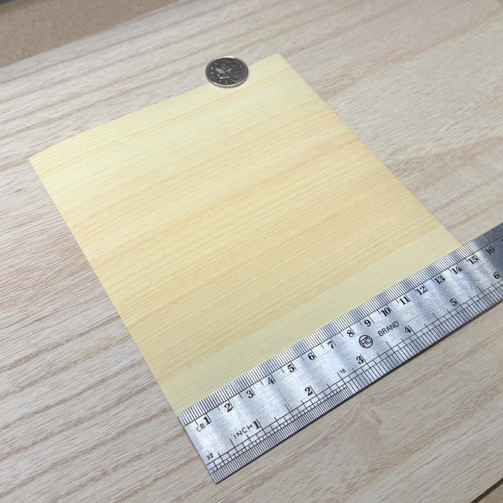 Hinoki cypress wood veneer sheet shown next to a ruler for scale, 5-7/8 inch square and 0.15 mm thick