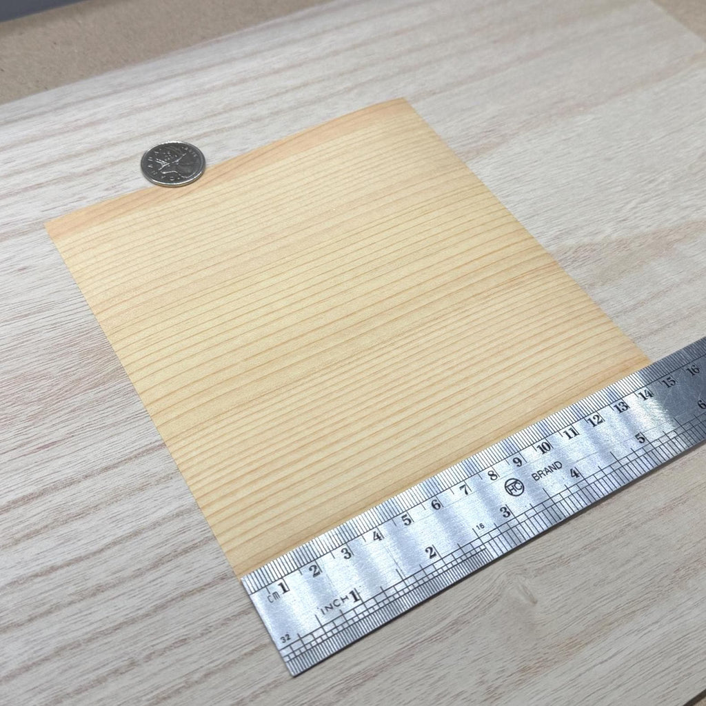 Douglas fir wood veneer sheet shown next to a ruler for scale, 5-7/8 inch square and 0.15 mm thick