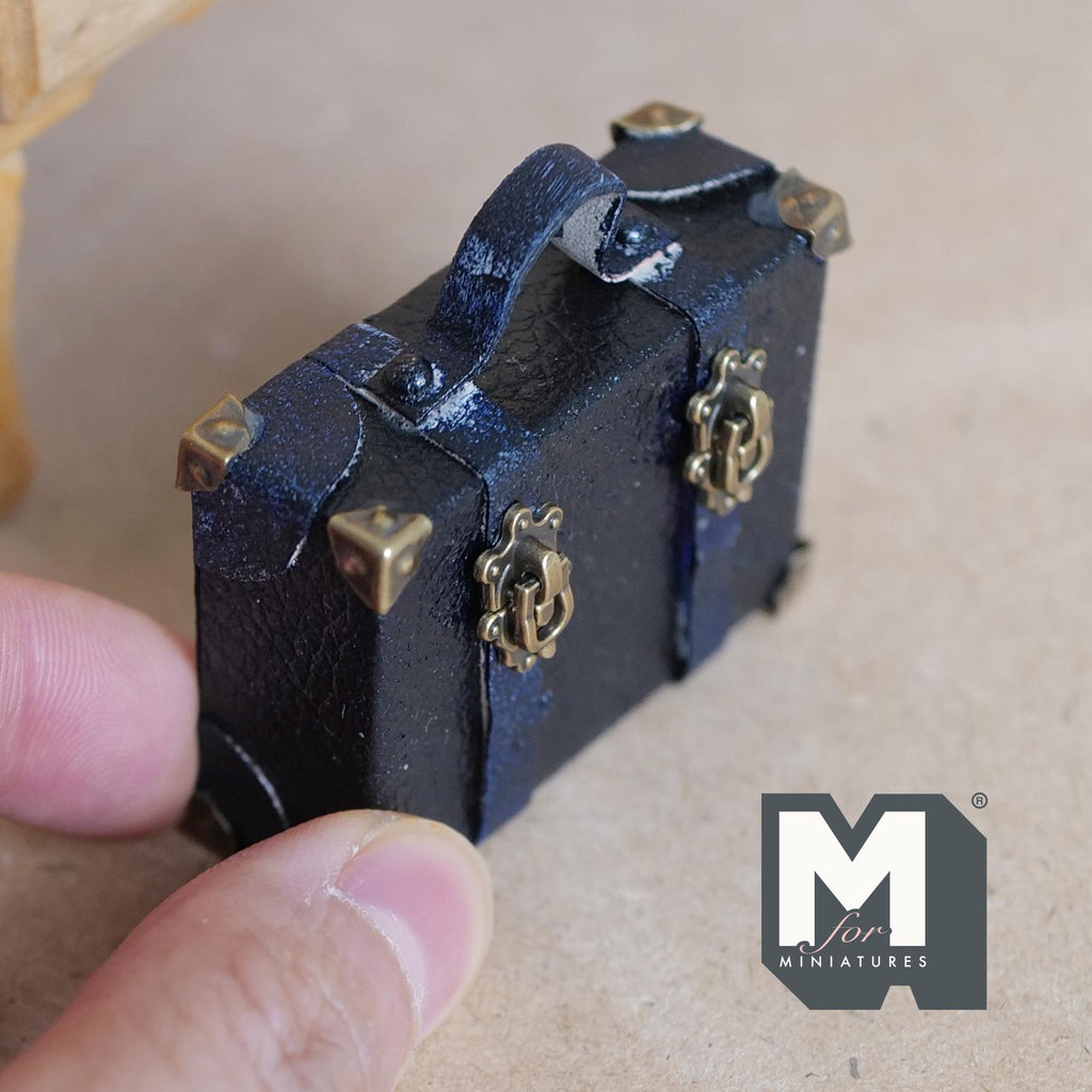 1:12 scale miniature navy faux leather suitcase with an aged worn finish, eight antique copper corner caps, two latch clasp straps and a top handle