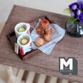 1:12 scale miniature lemon tea tray with two white mugs with red tulips and red handles, lemon slices, and assorted cookies on baking paper on a dark wood tray