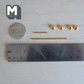 Unassembled 1:12 scale miniature gold towel bar and toilet paper holder set: four round end knobs with backplates and two gold rods laid beside a ruler and coin