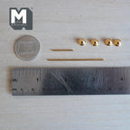 Unassembled 1:12 scale miniature gold towel bar and toilet paper holder set: four round end knobs with backplates and two gold rods laid beside a ruler and coin