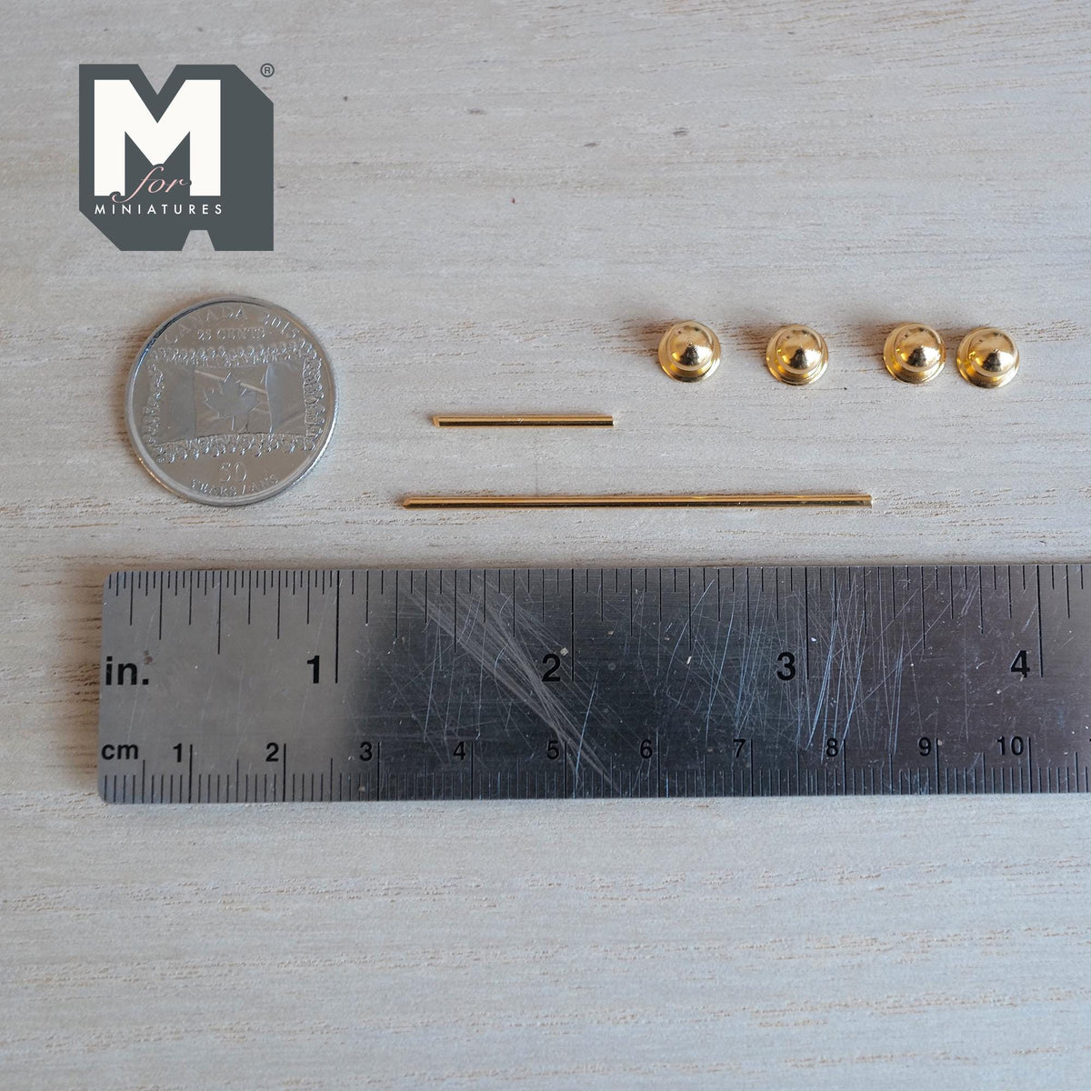 Unassembled 1:12 scale miniature gold towel bar and toilet paper holder set: four round end knobs with backplates and two gold rods laid beside a ruler and coin
