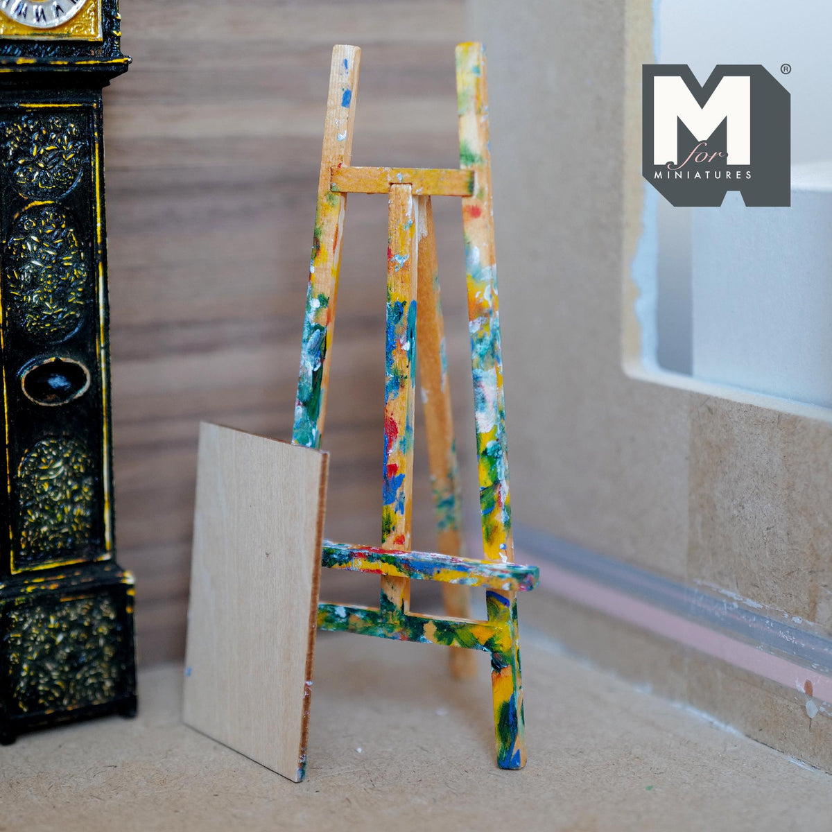 1:12 scale miniature wood tripod artist easel splattered with colorful paint, with a blank painting board leaning beside it
