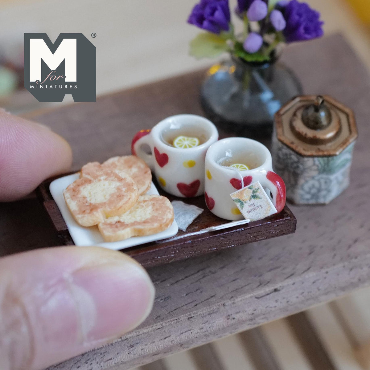 1:12 scale miniature wood tea tray with two white mugs with red hearts filled with lemon tea, and assorted cookies on baking paper