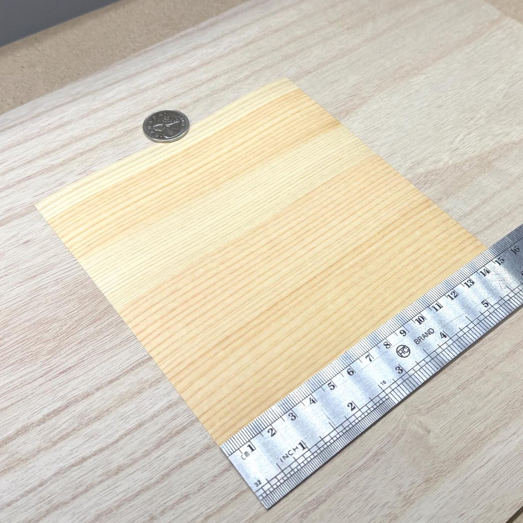 Pine wood veneer sheet shown next to a ruler for scale, 5-7/8 inch square and 0.15 mm thick