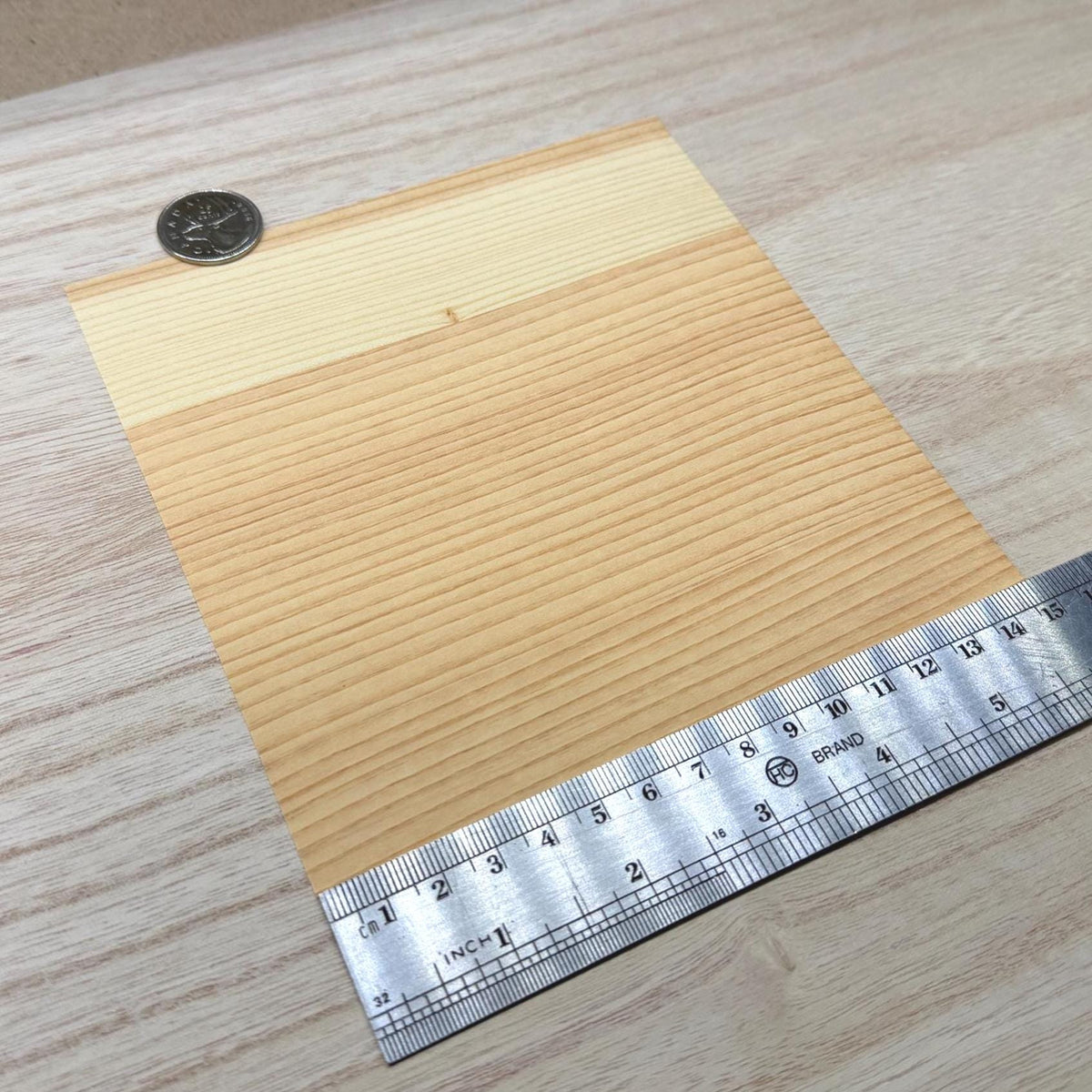 Cedar wood veneer sheet shown next to a ruler for scale, 5-7/8 inch square and 0.15 mm thick