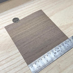 Walnut wood veneer sheet shown next to a ruler for scale, 5-7/8 inch square and 0.15 mm thick