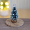 1:12 scale miniature frosted bottle brush Christmas tree with blue and white beads and a clear bead topper, shown on a round wood base