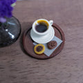 1:12 scale miniature cream cup of black coffee with crema on a saucer, with two chocolate cookies on deli paper, on a round brown serving tray