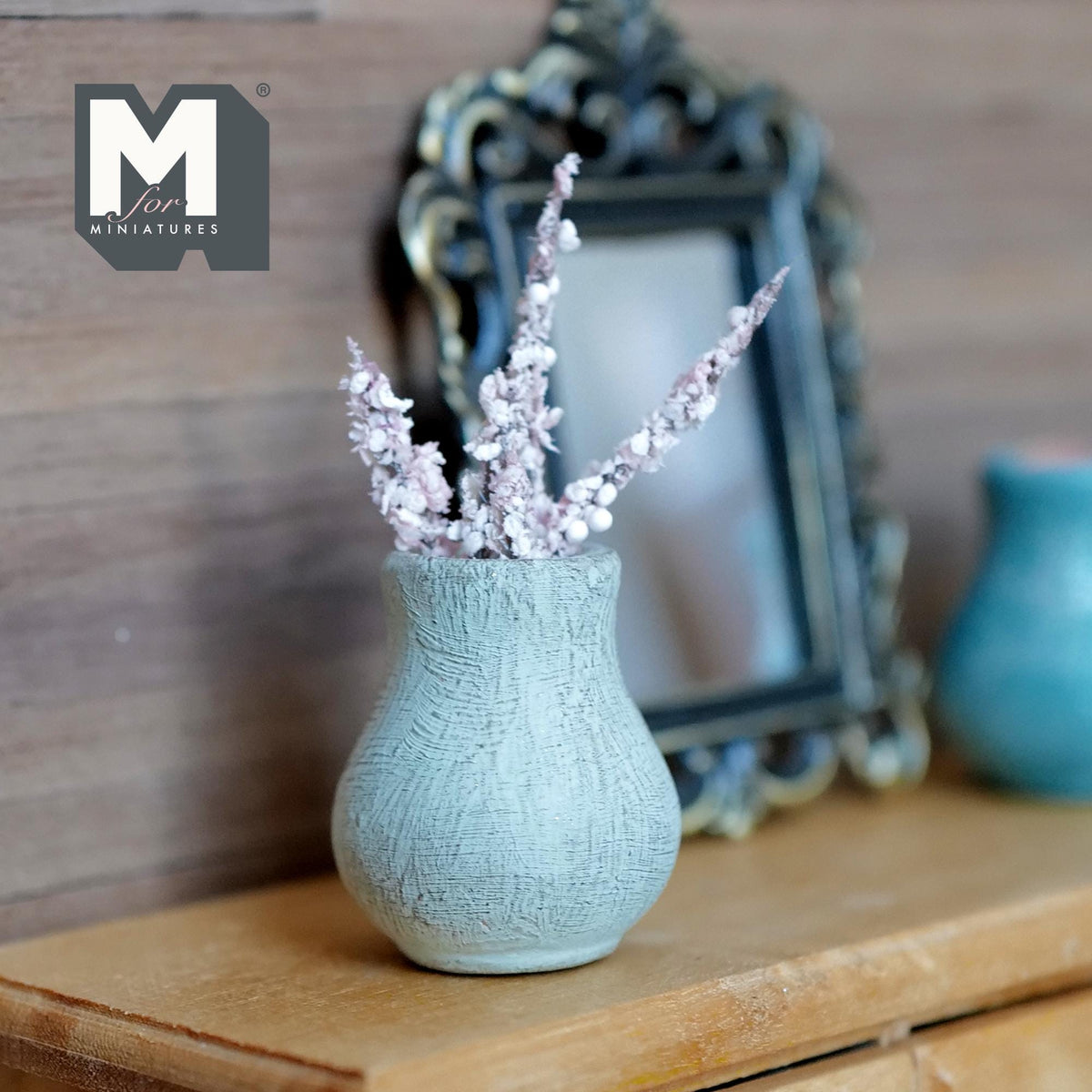 1:12 scale miniature weathered light blue clay bud vase with a round body and flared lip, holding pale pink blossom branches