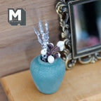 1:12 scale miniature weathered teal clay plum shaped vase with a short neck, holding silver stems and small white berries