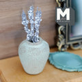 1:12 scale miniature weathered mint green clay plum shaped vase with a short neck, holding a bunch of sparkly silver flower stems