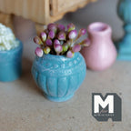 1:12 scale miniature weathered teal clay urn pot with fluted sides and a dotted band, planted with pink and purple flower buds