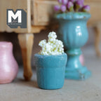 1:12 scale miniature weathered teal clay tapered pot with a raised rim band, planted with a cluster of small white flowers