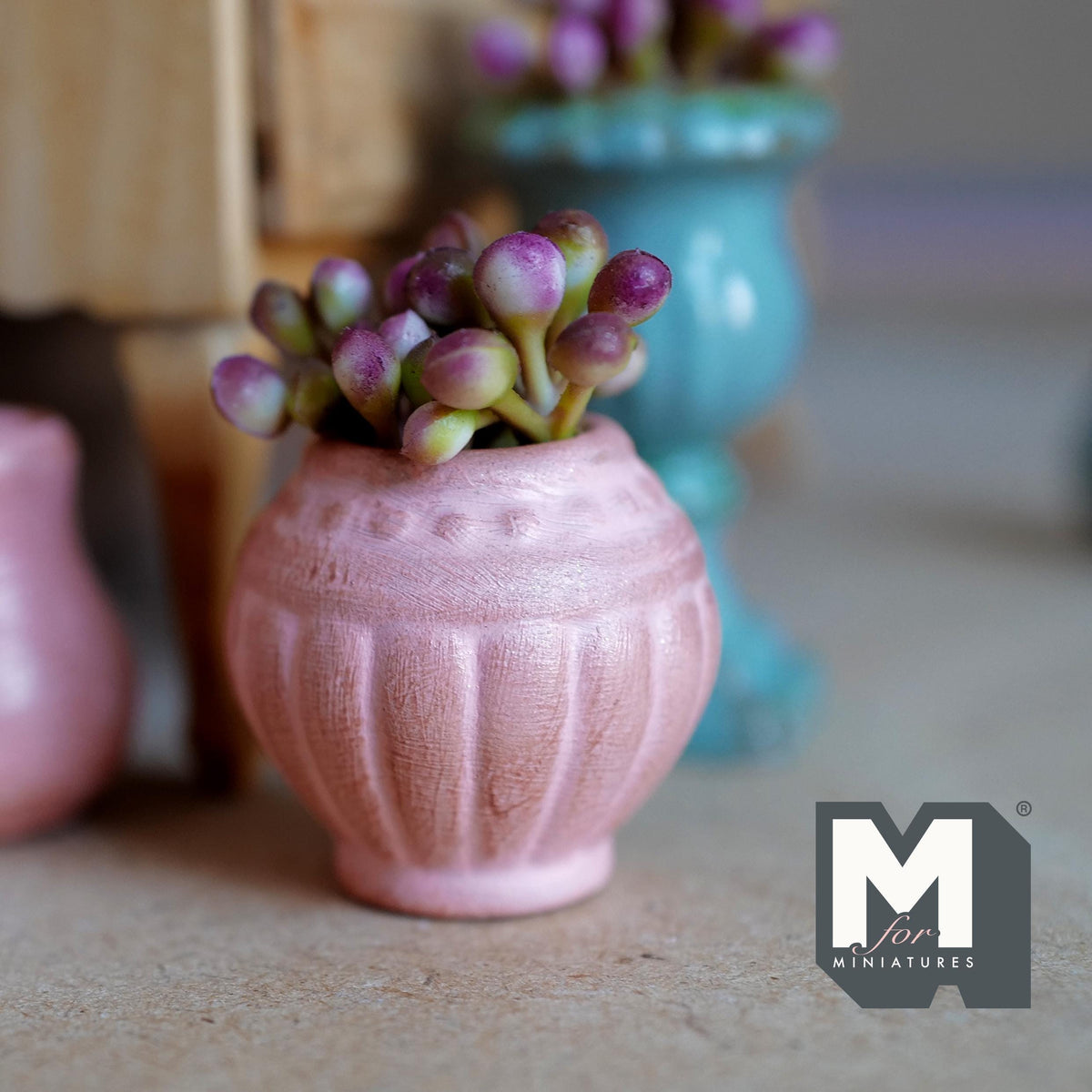 1:12 scale miniature weathered pink clay urn pot with fluted sides and a dotted band, planted with pink and purple flower buds