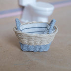 1:12 scale miniature two-tone woven laundry basket with a natural top, gray lower band and gray handles, lined with white and navy striped fabric